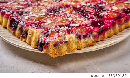 Macro panoramic view pie or tart with plums on plate on light wooden background Macro panoramic view pie or tart with plums on plate on light wooden background 83379182