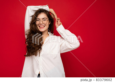 Portrait of beautiful positive cheerful cute smiling young brunette woman in casual white shirt and 83379602