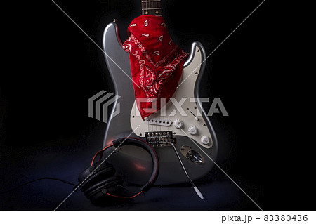 Silver electric guitar with red bandana isolated on black background Silver electric guitar with red bandana isolated on black background 83380436