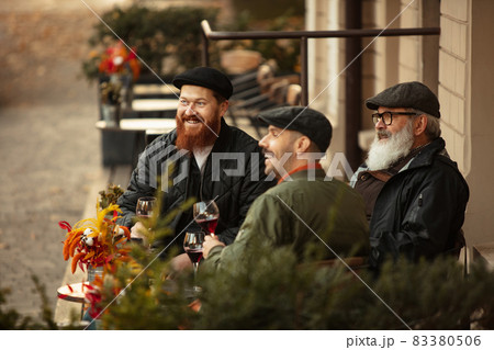 Group of men, friends having a meeting at cafe on warm autumn day. Drinking red wine, clinking glasses 83380506