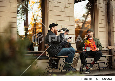 Group of men, friends having a meeting at cafe on warm autumn day. Drinking red wine, clinking glasses 83380508