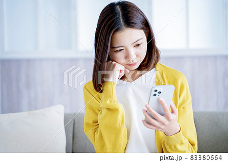 自宅でスマホを見る女性 83380664