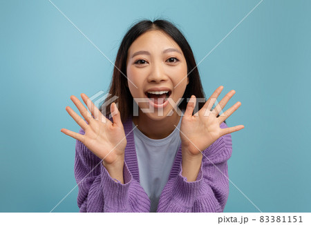 Positive emotions. Portrait of excited iasian lady screaming with joy and spreading hands, posing over blue background Positive emotions. Portrait of excited iasian lady screaming with joy and spreading hands, posing over blue background 83381151