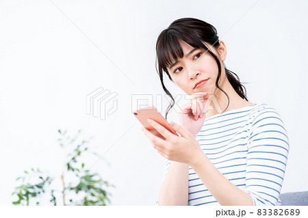 ソファでくつろぎながらスマホを操作する女性。 83382689