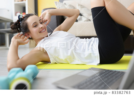 Woman doing sports workout on floor in front of laptop 83382763