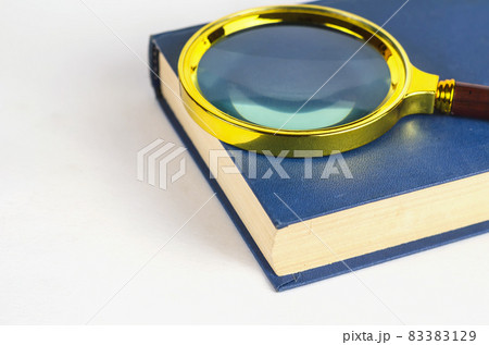 Magnifying glass and blue closed book in hardcover. Minimalist c 83383129