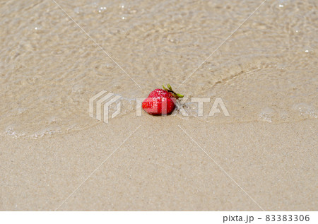A ripe red strawberry on the wet yellow sand. The strawberry lie 83383306