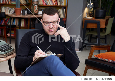 Therapist writing down notes during therapy sitting in a chair 83384466
