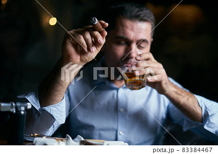 portrait of hansome man smoking cigar in a lounge bar 83384467