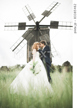 Stylish couple of happy newlyweds walking in the park on their wedding day with bouquet 83385462