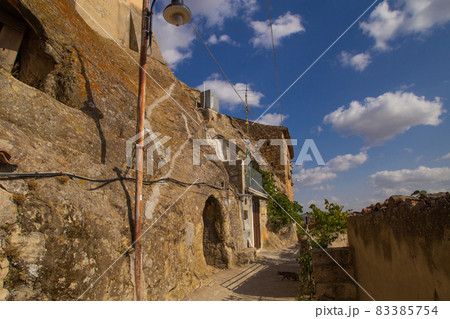 Abandoned houses in a rock in Sperlinga Sicily. Sandstone walls arch doors. One of the most beautiful borgo in Italy, a touristic attraction. Sunny photo good for travel agency booklet, poster or ads. 83385754