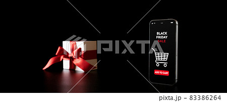 Sale gift. Internet online shopping app on mobile phone, white gift box with red ribbon isolated on black background in Black Friday concept. Discount sale. Sale gift. Internet online shopping app on mobile phone, white gift box with red ribbon isolated on black background in Black Friday concept. Discount sale. 83386264