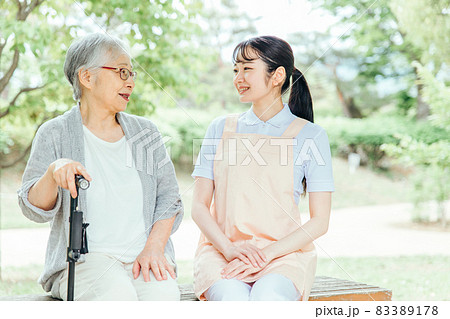 公園のベンチに座る高齢者と女性スタッフ（話す） 83389178