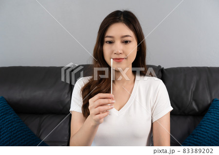 woman using coronavirus(covid-19) rapid antigen self test kit (atk) at home with cotton nasal swab 83389202