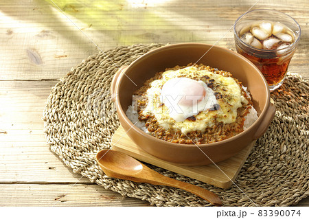 温泉卵とチーズが乗っている焼きドライカレーと木のスプーンとお茶 温泉卵とチーズが乗っている焼きドライカレーと木のスプーンとお茶 83390074