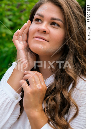 Young beautiful woman with a bright shining make up on a green meadow. High Fashion model woman in colorful bright silver sparkles. Glitter Vivid makeup Beautiful hair Girl. Healthy Long Hair 83392853