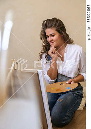 Creative painter in working process. Artist workplace, hobby, craft tools. Artist female canvas painting. Professional young woman painter draws in the workshop Creative painter in working process. Artist workplace, hobby, craft tools. Artist female canvas painting. Professional young woman painter draws in the workshop 83392868
