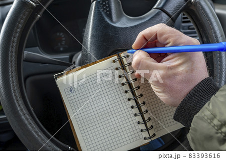 paper notebook in the driver hand, in which a man writes notes 83393616