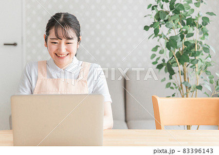パソコンを使うエプロン姿の女性（笑顔） 83396143