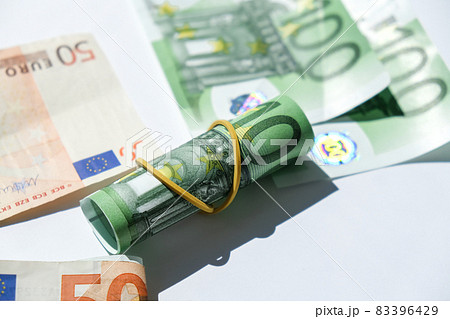 Close up of Euro money roll. Euro banknote set cash money - EU currency. Rolled with rubber euro notes. Banknotes stacked on each other in different positions Close up of Euro money roll. Euro banknote set cash money - EU currency. Rolled with rubber euro notes. Banknotes stacked on each other in different positions 83396429
