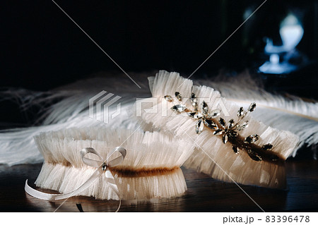 Two white garters of the bride are lying on the table 83396478