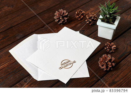Open envelope with blank letterhead on wooden background with pine cones and small plant in a pot Open envelope with blank letterhead on wooden background with pine cones and small plant in a pot 83396794
