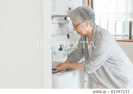 洗濯機を使う高齢者女性 83397232