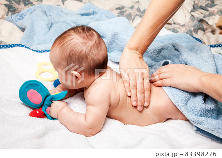 Little baby receiving chiropractic treatment of her back at home 83398276
