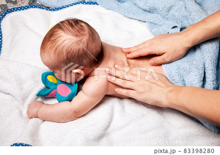 Little baby receiving chiropractic treatment of her back at home 83398280