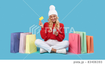 Smiling lady with shopping bags using cellphone and plastic card 83406393