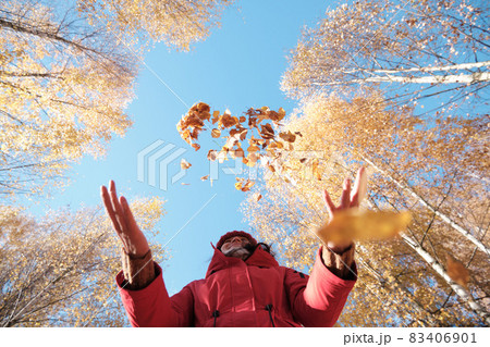 A Woman in A Red Jacket Throws Yellow Leaves. Autumn Landscape. Slow motion video. 83406901