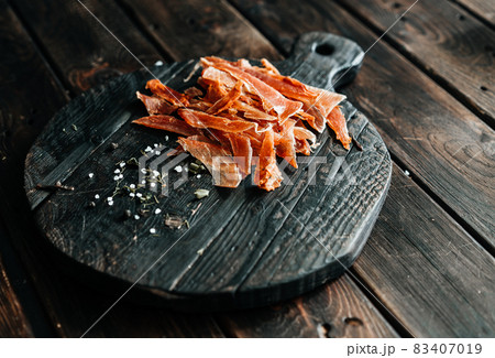 Dried chicken cut into strips on a wooden board with salt and pepper 83407019