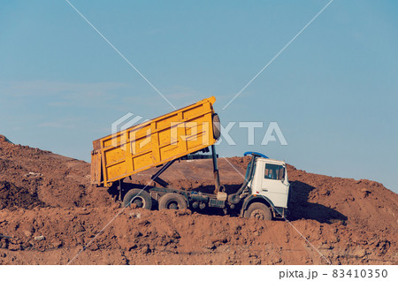 Dump truck is dumping gravel on an excavation site 83410350