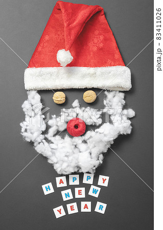 Composition with Santa's hat, walnuts, a ball of thread and fiberfill. Funny santa claus face. New Year card 83411026