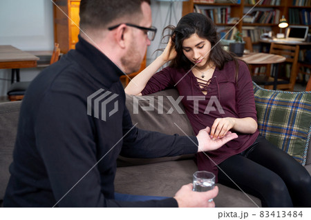 Therapist giving pills to a young woman patient during therapy session Therapist giving pills to a young woman patient during therapy session 83413484