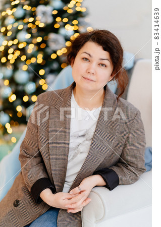 middle-aged brunette woman without makeup on the background of a christmas tree 83414639