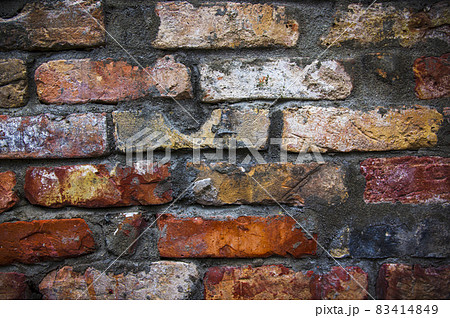 Grey white black red orange old vintage brick wall background. Rustic cemented dark brick house wall texture with grunge surface. Shabby Building Facade With Damaged Plaster. Aged weathered exterior 83414849