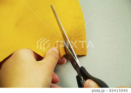 Closeup of fashion designer's hands cutting cloth with scissors in workshop. 83415040