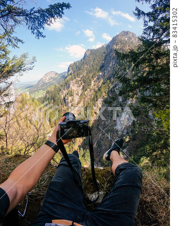 A photographer observes with his camera in hand from the top of a mountain. 83415302