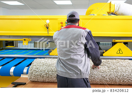 Laundry worker in the process of working on automatic machine for carpet washing in dry cleaning 83420612