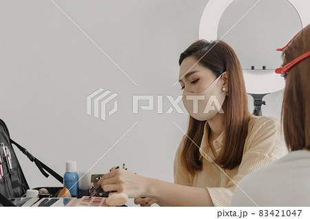 Woman makeup artist is at work and wearing makeup on her model. 83421047