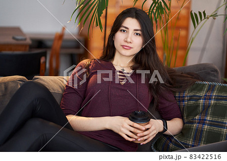 Enjoy weekend. Asian girl relaxing, drinking coffee and sitting on a couch Enjoy weekend. Asian girl relaxing, drinking coffee and sitting on a couch 83422516