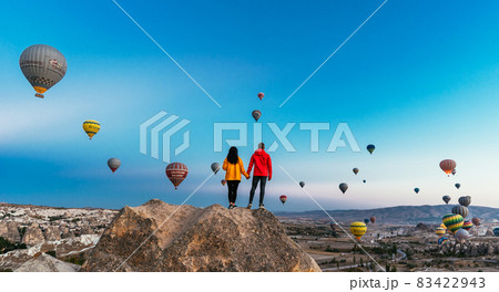 Couple in love among balloons. Happy couple in Cappadocia. Honeymoon in the mountains. Man and woman traveling. Flying on balloons. Festival of balloons Couple in love among balloons. Happy couple in Cappadocia. Honeymoon in the mountains. Man and woman traveling. Flying on balloons. Festival of balloons 83422943