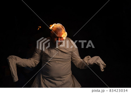 Bald man in a straitjacket with a burning head on a dark background. 83423034