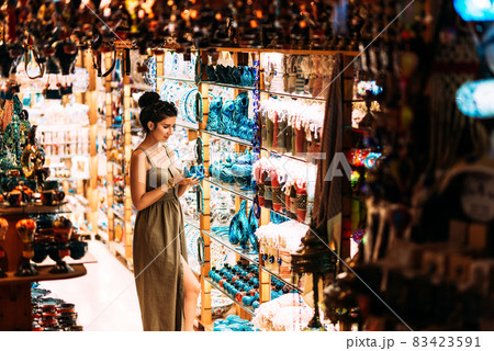 Beautiful girl in a souvenir shop in Turkey. Girl chooses a souvenir. Oriental shop. Turkish Souvenirs. Oriental bazaar. Turkish Bazaar. Gift shop in Goreme, Turkey. Moroccan Bazaar. Copy space. 83423591