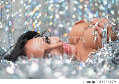 Caucasian nude woman lies in Christmas tinsel rain 83431674