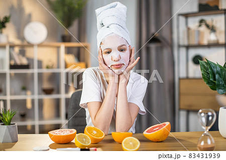 Female with towel on head using cosmetic mask for face Female with towel on head using cosmetic mask for face 83431939