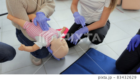 Closeup of first aid instructor using infant dummy demonstrating how to rescue a suffocating baby. 83432629