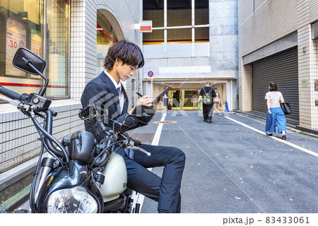 大型バイクのレビューを記入する若いビジネスマン 83433061