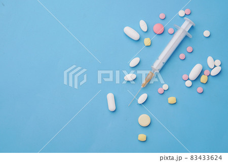 syringe and pills on blue background, close up 83433624